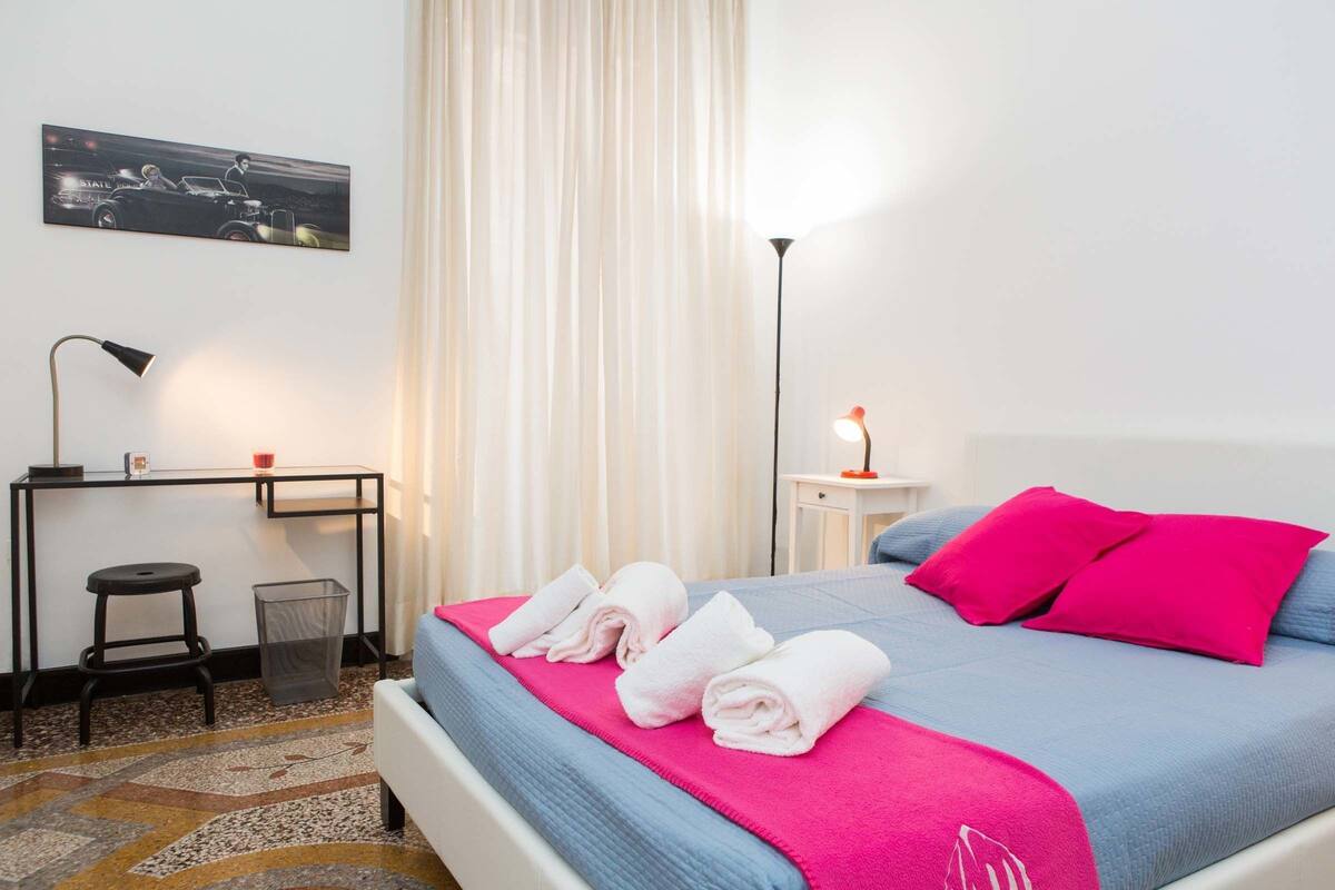 A neatly arranged hotel room with a bed, a desk, and a chair.