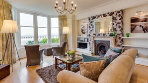 A spacious living room with a chandelier, large windows, a fireplace, and a sofa. - Number 43 (Carnforth)