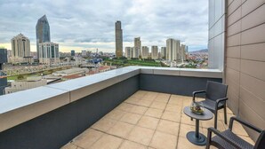 A balcony with a city view, including high-rise buildings and a bridge.