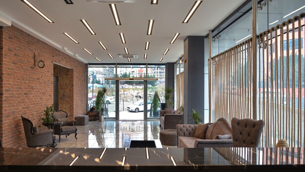A modern lobby with a brick wall, leather sofas, and a glass partition.