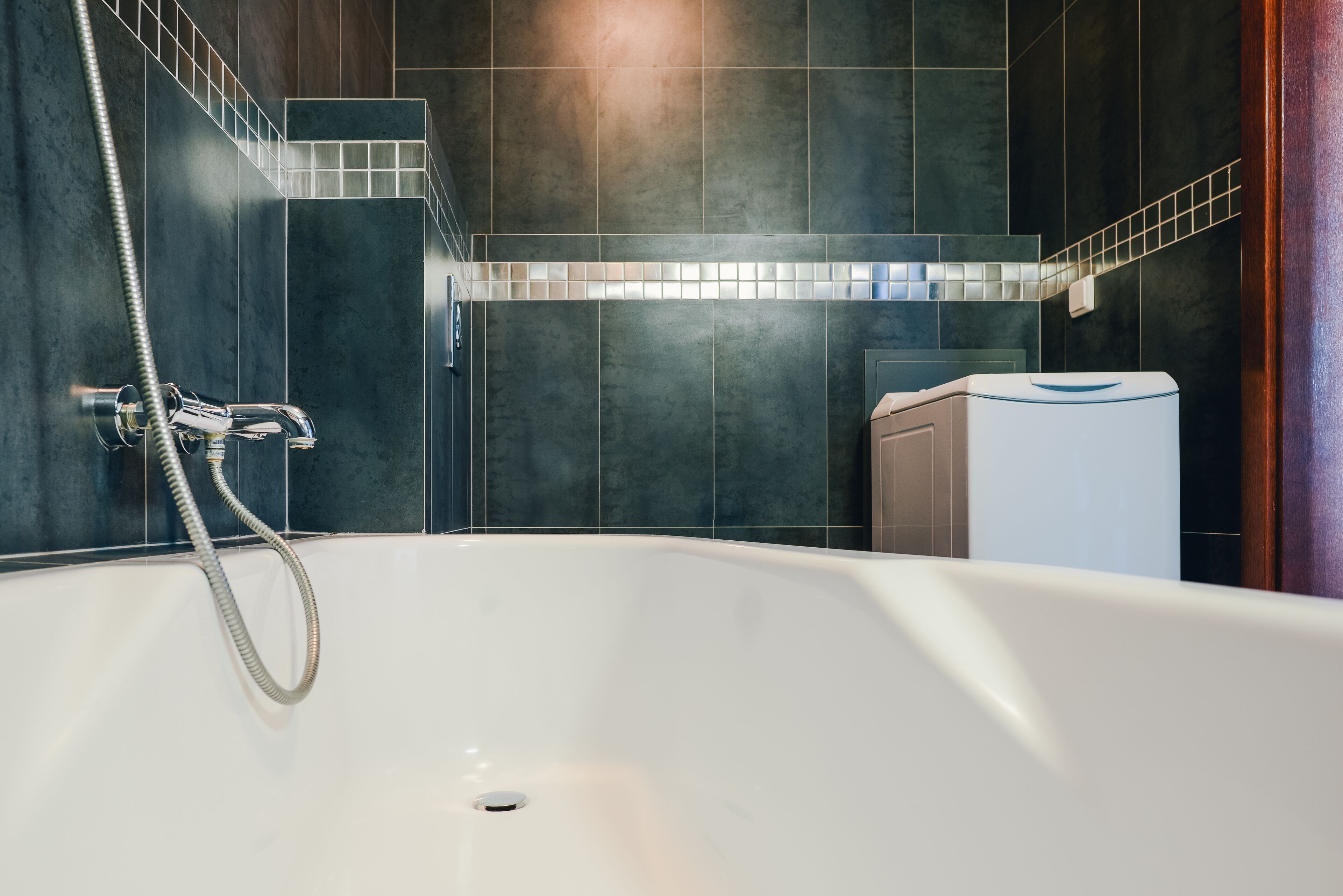 A modern bathroom with a freestanding bathtub, a showerhead, and a towel rack.