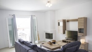 Una sala de estar moderna con un sofá gris, una mesa de centro de madera, un televisor y una chimenea.