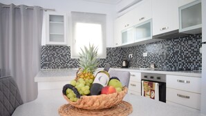 Una cocina moderna con armarios blancos, salpicadero de azulejos y una cesta de frutas en la encimera.