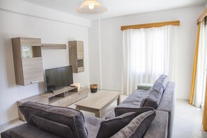Una sala de estar moderna con televisor, sofá y una mesa de centro de madera.
