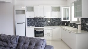 Una cocina moderna con armarios blancos, un salpicadero de azulejos negros y un horno empotrado.