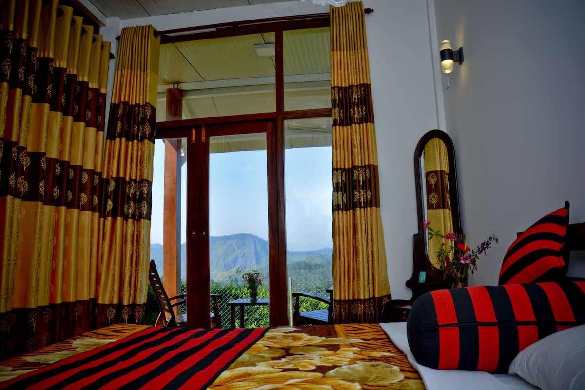 A room with a bed, curtains, a mirror, and a view of mountains.
