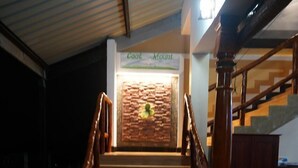 A staircase with wooden railings leading to a reception area with a brick wall and a sign that reads "Cool Mount". - Cool Mount Resort (Ballaketuwa)
