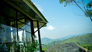 A building with a metal roof and large windows overlooking a mountainous landscape. - Cool Mount Resort (Ballaketuwa)