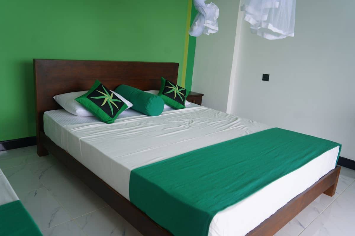 A bed with a wooden headboard, green bedding, and a green throw blanket.