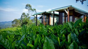 A two-story building with a sloped roof, surrounded by lush greenery and hills in the background. - Cool Mount Resort (Ballaketuwa)