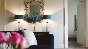 A room with a dark blue sofa, two lamps, a mirror, and a vase with flowers. - 15 Glasgow (Glasgow)