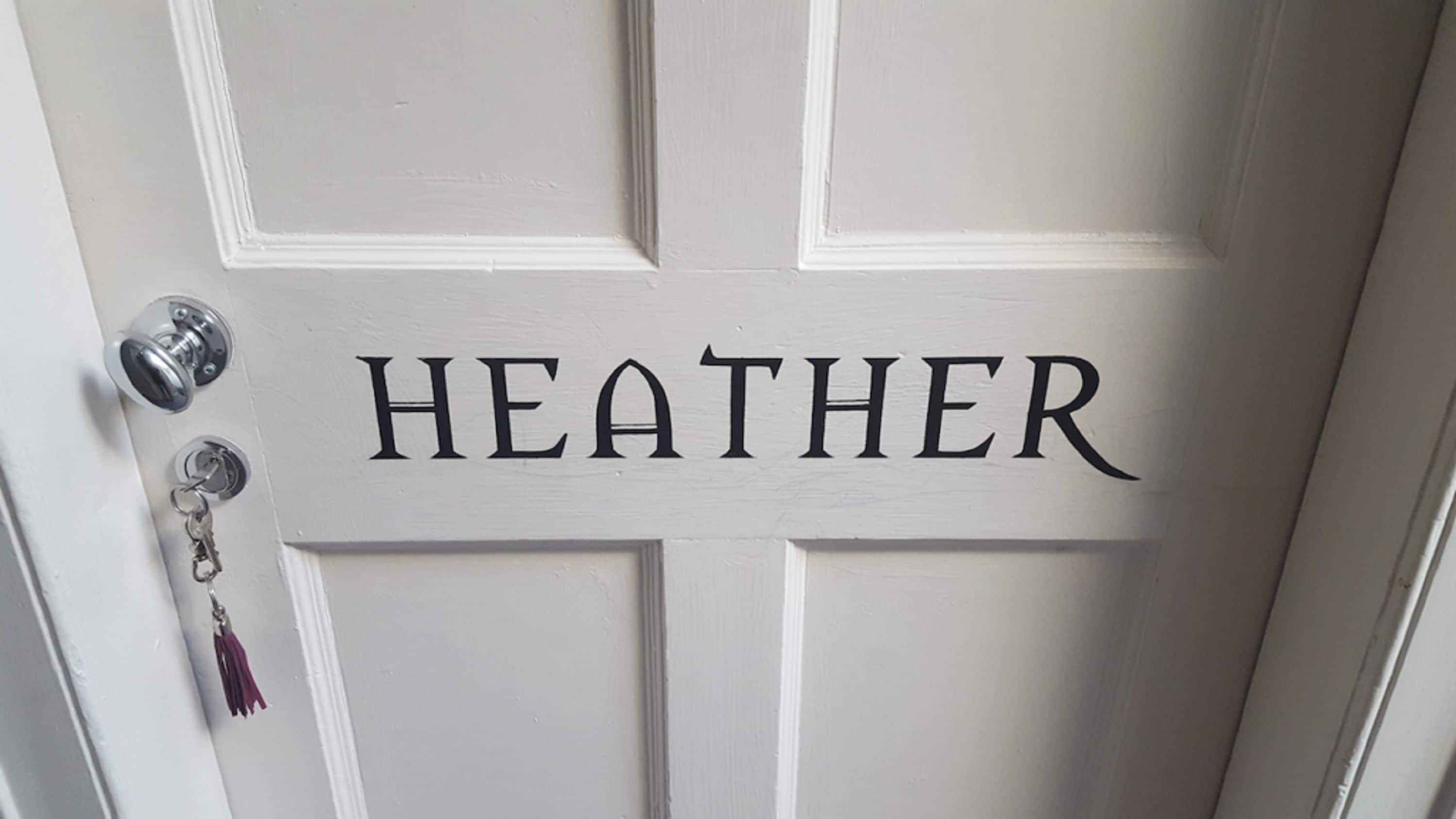 A white door with the name "HEATHER" in black letters.