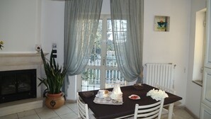 A dining area with a table set for two, a potted plant, and a fireplace. - Maison Blanche (Pompei)
