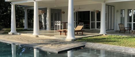 A two-story house with a pool, white columns, and a balcony.