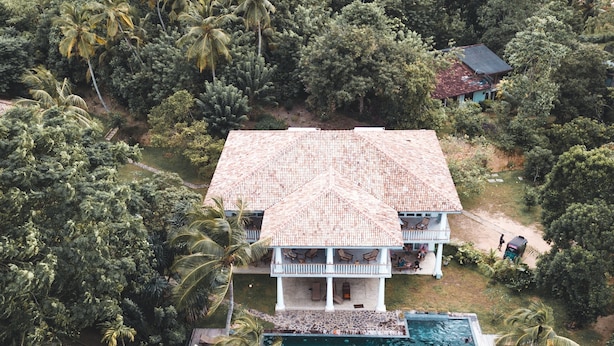 A two-story house with a tiled roof, surrounded by dense tropical vegetation. - Good Vibes Villas Retreat And Restaurant (Unawatuna)
