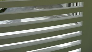 A view through white blinds with a glimpse of a building's interior and exterior. - Good Vibes Villas Retreat And Restaurant (Unawatuna)