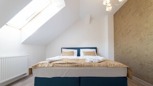 Un dormitorio con tragaluz, cama con cabecera azul y suelo de madera.