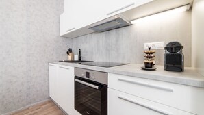 Una cocina moderna con armarios blancos, horno Bosch, cafetera y campana extractora integrada.