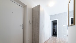 Un pasillo con una puerta blanca, un armario y un baño a lo lejos.