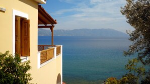 Ein Gebäude mit einem Balkon mit Blick auf ein ruhiges Meer und ferne Berge.