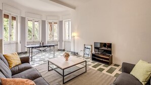 Una sala de estar con sofá, mesa de centro, televisión y un comedor con mesa y sillas.