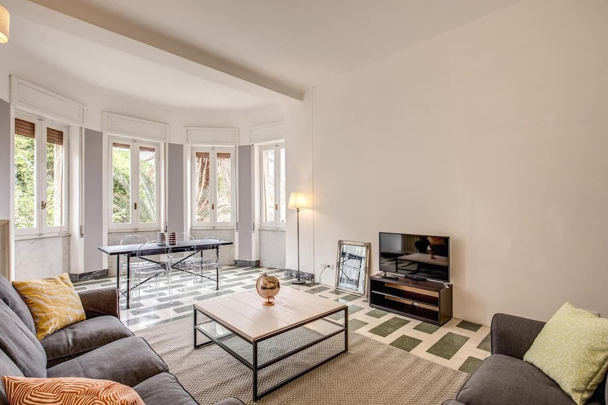 A living room with a sofa, coffee table, TV, and a dining area with a table and chairs.