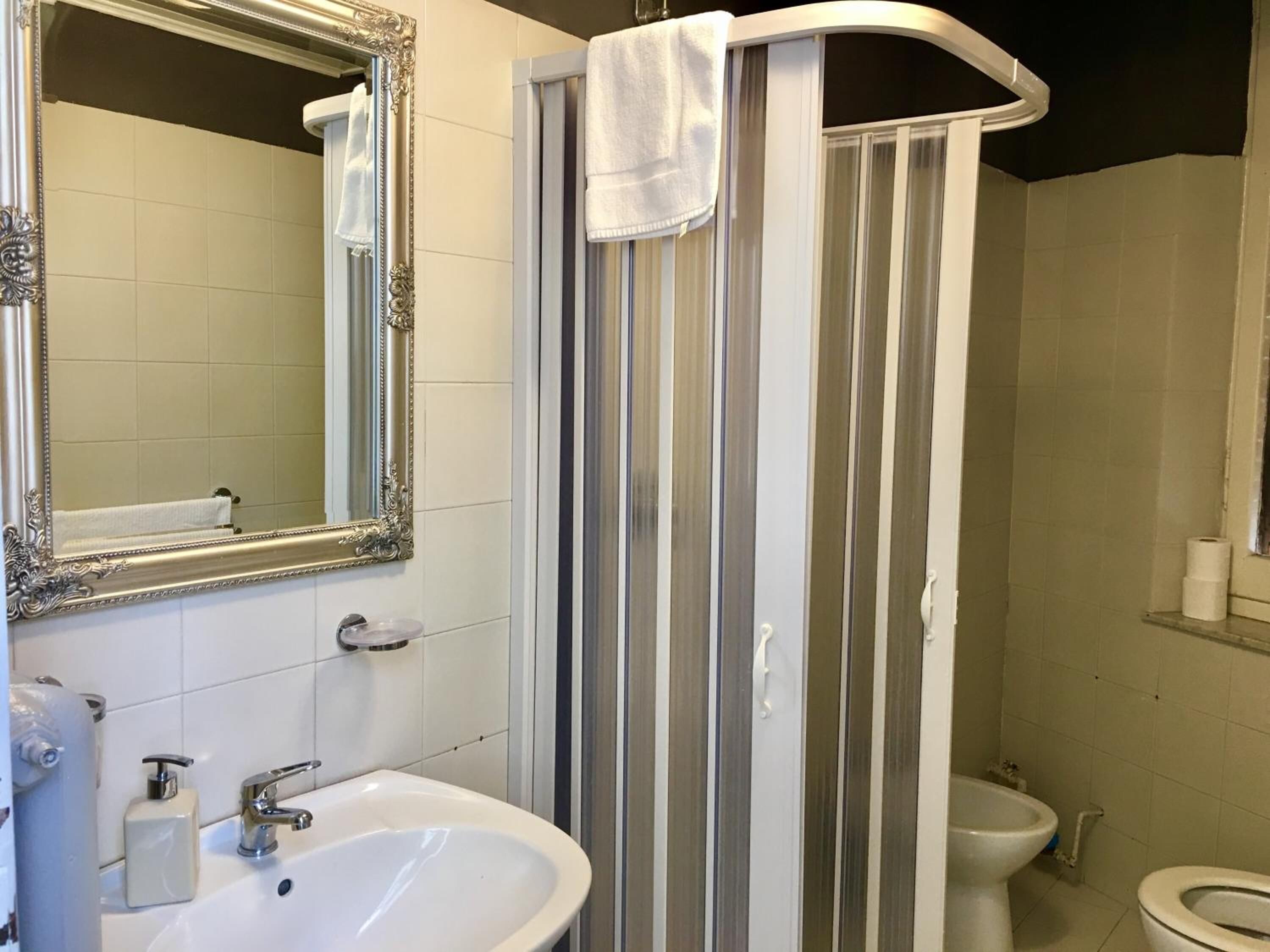 Ein Badezimmer mit Waschbecken, Spiegel, Dusche und Toilette.