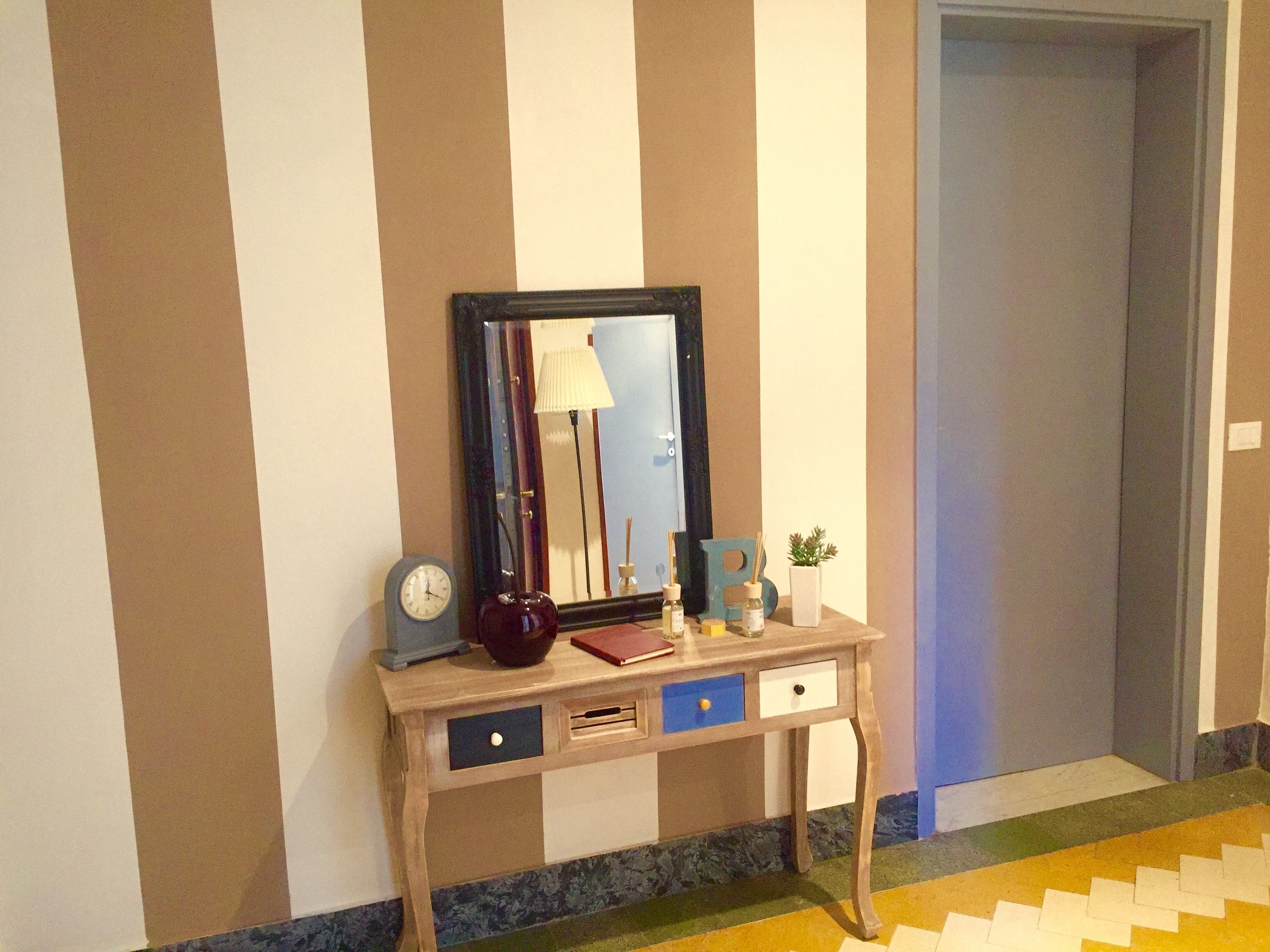 Una consola de madera con un espejo, un reloj, una lámpara y algunos objetos decorativos.