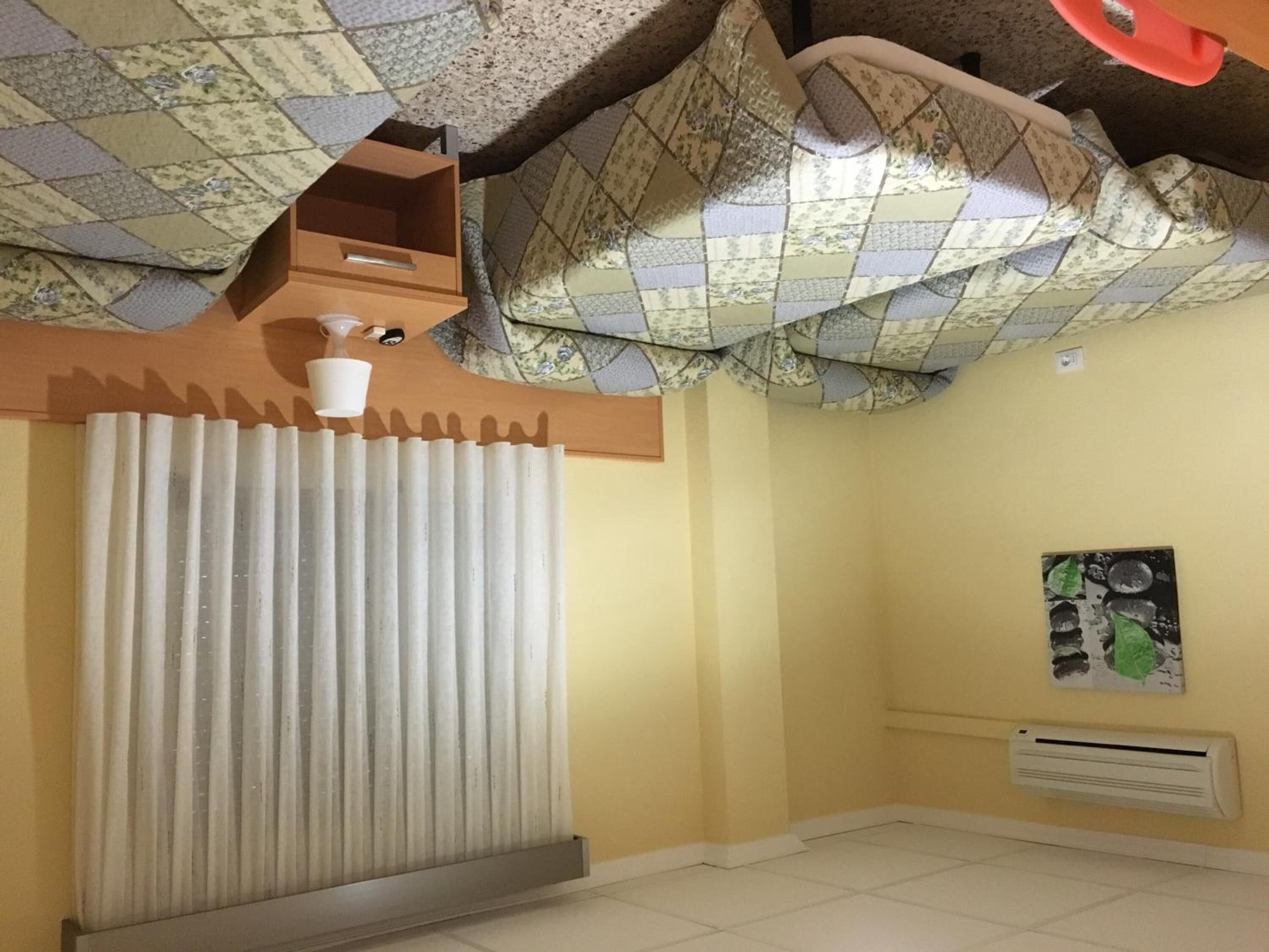 Una habitación con un radiador, una ventana con persianas verticales, un aire acondicionado de pared y un techo con diseño decorativo.