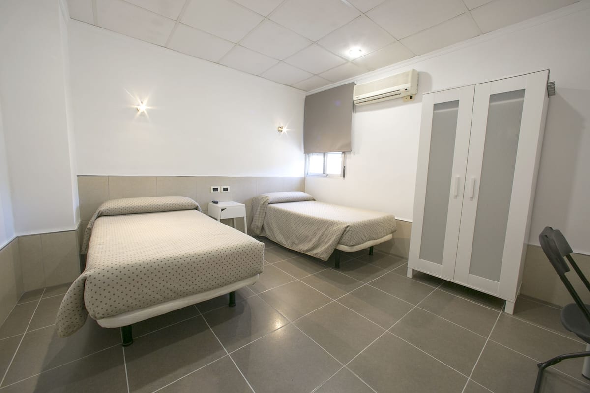 Ein Schlafzimmer mit zwei Betten, einem Kleiderschrank und einem kleinen Tisch.