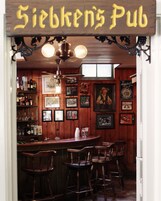 Interior de Siebken's Pub, con paredes de madera, una zona de bar y varias fotografías enmarcadas.