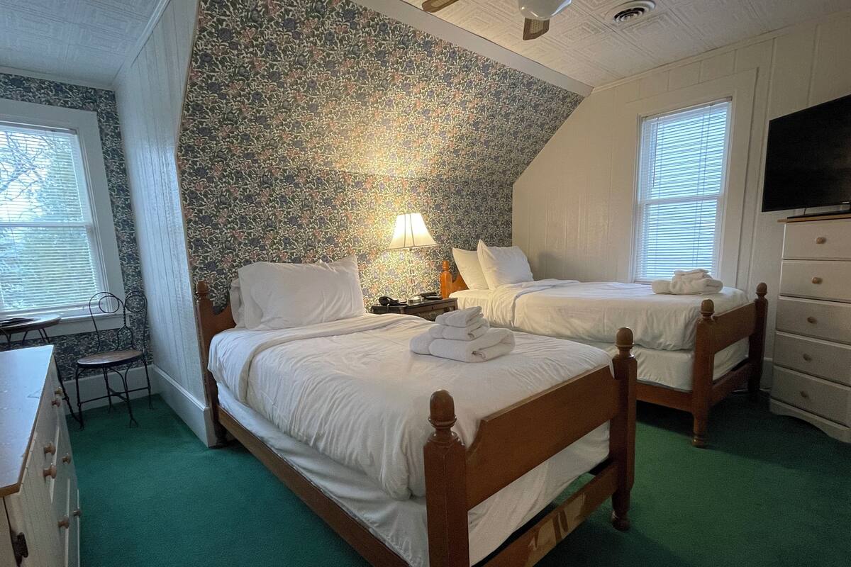 A bedroom with two beds, a desk, and a dresser.