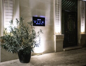 A potted plant in front of a building with a sign that reads "VIVA". - Viva Boutique Hotel (Baku)
