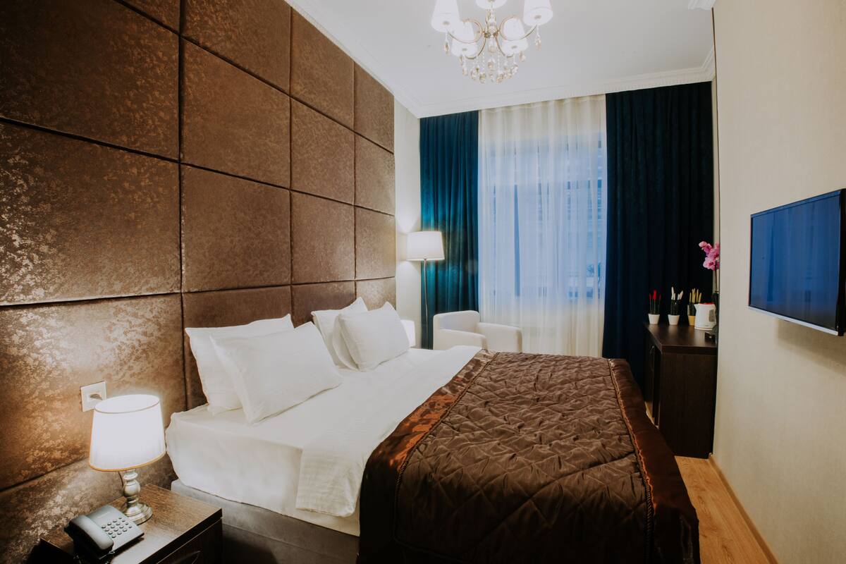 Une chambre d’hôtel avec un grand lit, une lampe de chevet, un téléphone, une télévision et une table de chevet.