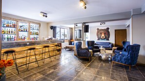 Una zona de bar con taburetes, un sofá y una decoración de pared con motivos de osos.