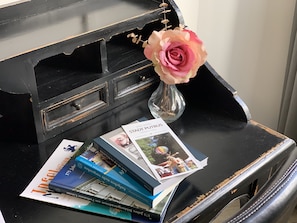 A black desk with a vase of pink flowers, several books, and a brochure titled "Stadt Putbus". - Parkhotel Putbus(Adults Only) (Putbus)
