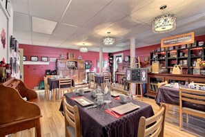 A restaurant with tables set for dining, a piano, and a display of general merchandise.