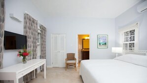 A hotel room with a bed, a desk, a chair, a TV, and a door leading to a bathroom. - Wag Water Villa, Ocho Rios 3BR (Ocho Rios)