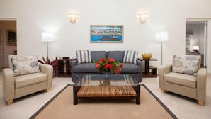 A living room with a sofa, two armchairs, a coffee table, and a painting on the wall. - Wag Water Villa, Ocho Rios 3BR (Ocho Rios)