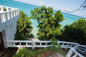 A white building with a balcony overlooking a turquoise sea and lush greenery. - Wag Water Villa, Ocho Rios 3BR (Ocho Rios)