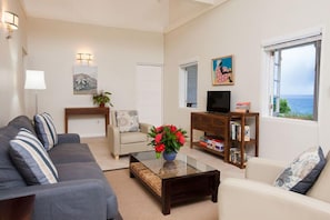 A living room with a sofa, a coffee table with a vase of flowers, a television, and a bookshelf.