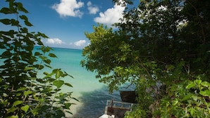 A view of a beach with clear turquoise water, surrounded by lush greenery and a white railing. - Wag Water Villa, Ocho Rios 3BR (Ocho Rios)