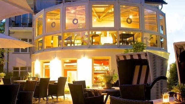 A two-story building with outdoor seating and a restaurant area. - Hotel Residenz Lauterbach  (Putbus)