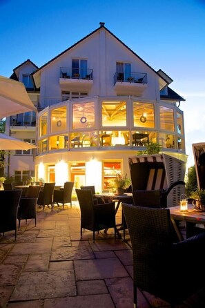 A two-story building with outdoor seating and a restaurant area. - Hotel Residenz Lauterbach  (Putbus)
