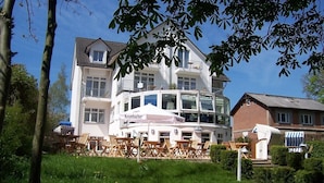 A multi-story building with a balcony, outdoor seating area, and a sign reading "Krombacher." - Hotel Residenz Lauterbach  (Putbus)