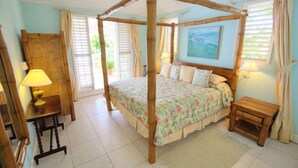 Una habitación con cama con dosel, una mesita de noche de madera, una pequeña mesa con lámpara y un cuadro en la pared.