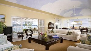 Un salón espacioso con un gran ventanal, una televisión y un comedor con mesa y sillas.