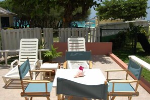 An outdoor seating area with white and blue chairs, a small table, and a potted plant. - Sea Wyf Cottage, Silver Sands 2BR (Duncans)