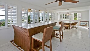 A spacious kitchen with a central island, white cabinetry, and large windows with shutters.