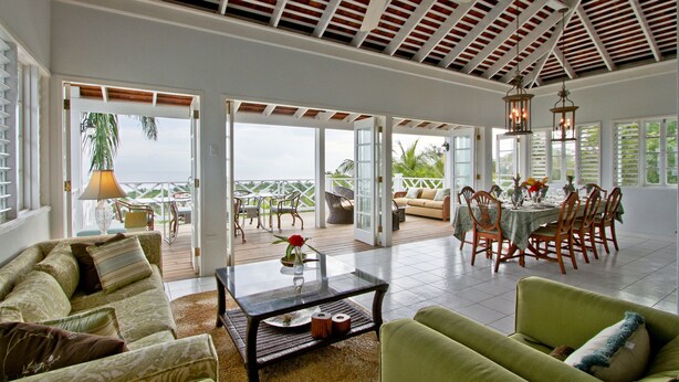 A spacious indoor area with a high ceiling, a dining table set for four, and a sofa in the foreground.